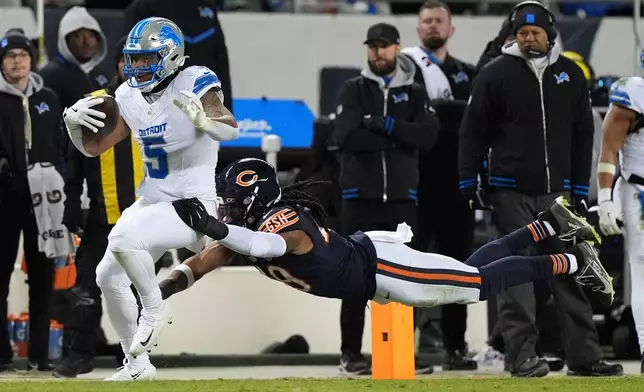 Detroit Lions running back David Montgomery (5) runs from Chicago Bears linebacker Tremaine Edmunds (49) during the second half of an NFL football game, Sunday, Jan. 4, 2026, in Chicago. (AP Photo/Nam Y. Huh)