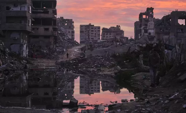 Palestinians walk amid buildings destroyed by Israeli air and ground operations in Gaza City, Thursday, Jan. 29, 2026. (AP Photo/Jehad Alshrafi)