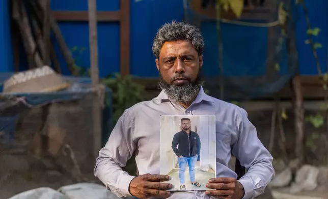 Mohammed Siraj holds a photograph of his 20-year-old son, Sajjad, who was killed after being taken to fight in Russia, at his home in Lakshmipur, Bangladesh, Dec. 10, 2025. (AP Photo/Rajib Dhar)