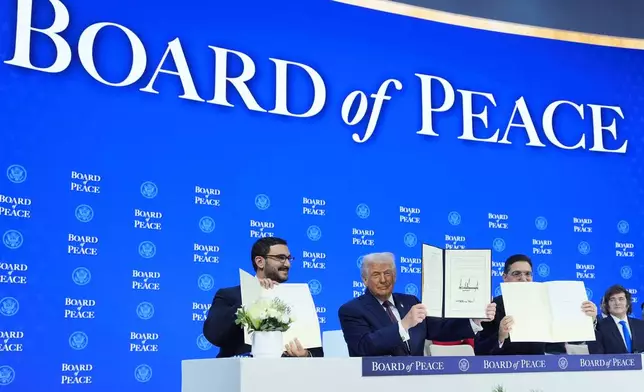 President Donald Trump, center, holds up a signed Board of Peace charter during the Annual Meeting of the World Economic Forum in Davos, Switzerland, Thursday, Jan. 22, 2026. (AP Photo/Evan Vucci)