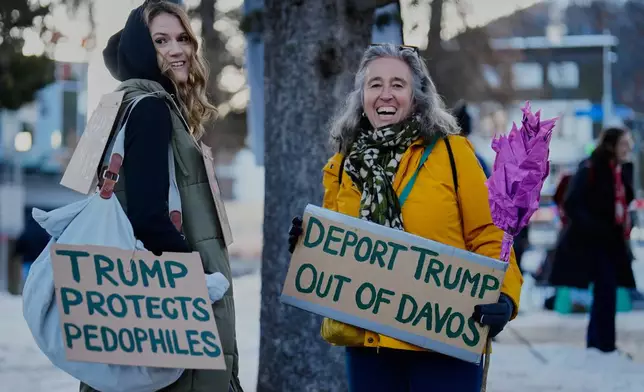 Two women with posters attend a demonstration against United States President Donald Trump and the Annual Meeting of the World Economy Forum in Davos, Switzerland, Sunday, Jan. 18, 2026. (AP Photo/Markus Schreiber)