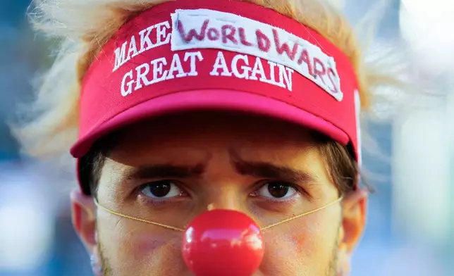 A man dressed as a clown waits for the start of a demonstration against President Trump and the Annual Meeting of the World Economy Forum in Davos, Switzerland, Sunday, Jan. 18, 2026. (AP Photo/Markus Schreiber)