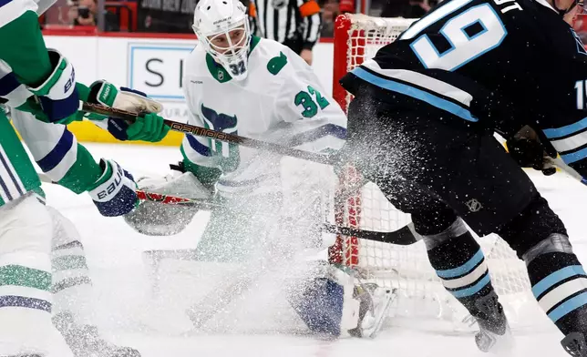 Carolina Hurricanes goaltender Brandon Bussi (32) watches the puck controlled by Utah Mammoth's Daniil But (19) during the first period of an NHL hockey game in Raleigh, N.C., Thursday, Jan. 29, 2026. (AP Photo/Karl DeBlaker)