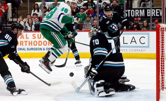 Carolina Hurricanes' Jordan Martinook (48) leaps out of the way of the puck in front of Utah Mammoth goaltender Karel Vejmelkab (70) with John Marino (6) and Nate Schmidt (88) during the second period of an NHL hockey game in Raleigh, N.C., Thursday, Jan. 29, 2026. (AP Photo/Karl DeBlaker)