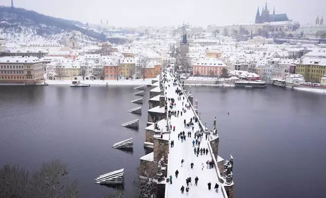 People cross the medieval Charles Bridge after a heavy snowfall in Prague, Czech Republic, Friday, Jan. 9, 2026. (AP Photo/Petr David Josek)