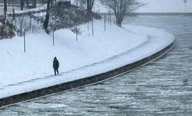 A pedestrian walks along the banks of the Neris river as temperatures dipped to -12 degrees Celsius (10,4 degrees Fahrenheit) in Vilnius, Lithuania, Friday, Jan. 9, 2026. (AP Photo/Mindaugas Kulbis)