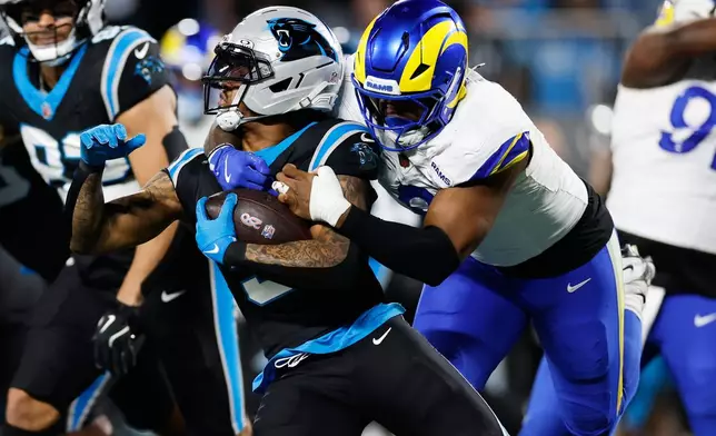 Carolina Panthers running back Rico Dowdle (5) is tackled by Los Angeles Rams linebacker Jared Verse during the first half of an NFL wild-card playoff football game, Saturday, Jan. 10, 2026, in Charlotte, N.C. (AP Photo/Rusty Jones)