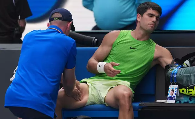 Carlos Alcaraz of Spain receives treatment during his semifinal match against Alexander Zverev of Germany at the Australian Open tennis championship in Melbourne, Australia, Friday, Jan. 30, 2026. (AP Photo/Dita Alangakra)