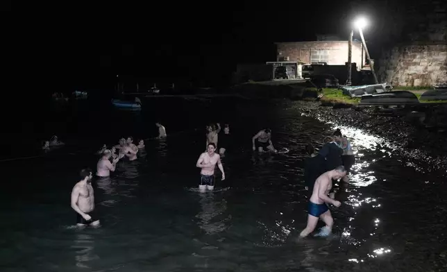 Rescue volunteers dive into the sea to celebrate after being acquitted of charges related to aiding migrants in Mytilene, on the northeastern Aegean island of Lesbos, Greece, Thursday, Jan. 15, 2026. (AP Photo/Panagiotis Balaskas)