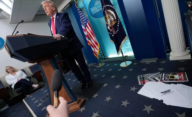 President Donald Trump speaks as White House press secretary Karoline Leavitt listens in the James Brady Press Briefing Room at the White House, Tuesday, Jan. 20, 2026, in Washington. (AP Photo/Alex Brandon)
