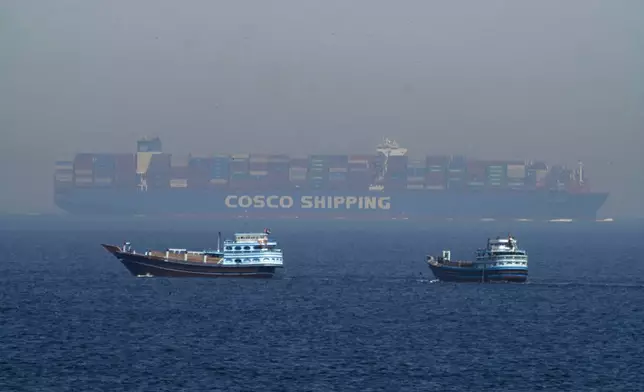 FILE - Two traditional dhows sail by a large container ship in the Strait of Hormuz, May 19, 2023. (AP Photo/Jon Gambrell, File)