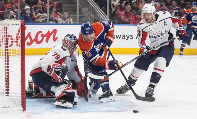 Washington Capitals' goalie Charlie Lindgren (79) makes a save against Edmonton Oilers' Zach Hyman (18) as Capitals' John Carlson (74) defends during second-period NHL hockey game action in Edmonton, Alberta, Saturday, Jan. 24, 2026. (Jason Franson/The Canadian Press via AP)