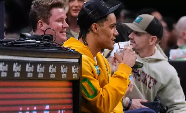 New England Patriots cornerback Christian Gonzalez, center, sits courtside during the second half of an NBA basketball game between the Boston Celtics and the Sacramento Kings, Friday, Jan. 30, 2026, in Boston. (AP Photo/Charles Krupa)