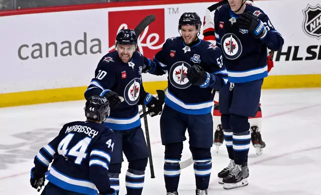 Winnipeg Jets' Tanner Pearson (70) celebrates after the winning goal against the New Jersey Devils with Josh Morrissey (44), Daniel Zhilkin (53) and Logan Stanley (64) in an NHL hockey game in Winnipeg, Manitoba, Sunday, Jan. 11, 2026. (Fred Greenslade/The Canadian Press via AP)