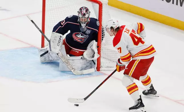 Columbus Blue Jackets' Jet Greaves, left, protects the net against Calgary Flames' Connor Zary during the second period of an NHL hockey game, Tuesday, Jan. 13, 2026, in Columbus, Ohio. (AP Photo/Jay LaPrete)