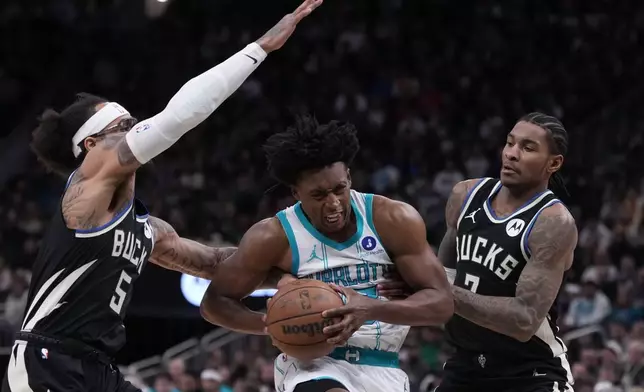 Charlotte Hornets guard Collin Sexton (8) drives between Milwaukee Bucks guard Kevin Porter Jr. (7) and guard Gary Trent Jr. (5) during the first half of an NBA basketball game Friday, Jan. 2, 2026, in Milwaukee. (AP Photo/Morry Gash)