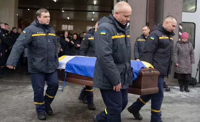 Rescuers carry the coffin of their fellow Oleksandr Zibrov, 36, who was killed in a secondary Russian drone strike on a residential building, at a fire station in Kyiv, Ukraine, Wednesday, Jan. 28, 2026. (AP Photo/Efrem Lukatsky)