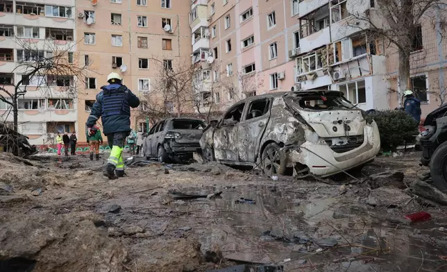 People pass by damaged cars near an apartment building after a Russian attack in Zaporizhzhia, Ukraine, Wednesday, Jan. 28, 2026. (AP Photo/Kateryna Klochko)