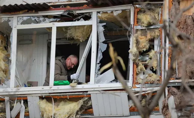 A local resident clears up debris from his broken balcony after a Russian attack in Zaporizhzhia, Ukraine, Wednesday, Jan. 28, 2026. (AP Photo/Kateryna Klochko)