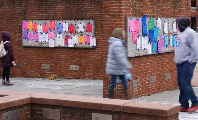People walk past posted signs on the locations of the now removed explanatory panels that were part of an exhibit on slavery at President's House Site in Philadelphia, Friday, Jan. 23, 2026. (AP Photo/Matt Rourke)