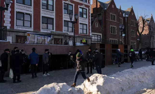 People walk near the scene where a car slammed into the entrance of the Chabad Lubavitch world headquarters, Thursday, Jan. 29, 2026, in New York. (AP Photo/Yuki Iwamura)