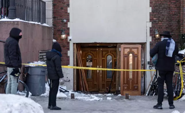 People watch the scene where a car slammed into the entrance of the Chabad Lubavitch world headquarters, Thursday, Jan. 29, 2026, in New York. (AP Photo/Yuki Iwamura)