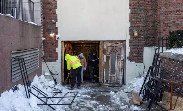 People clean up the scene where a car slammed into the entrance of the Chabad Lubavitch world headquarters, Thursday, Jan. 29, 2026, in New York. (AP Photo/Yuki Iwamura)