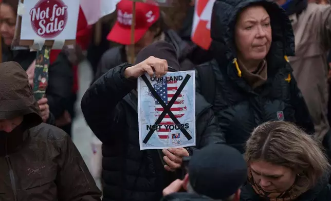 A man holds a map of Greenland covered in the American flag crossed out with an X during a protest against Trump's policy towards Greenland in front of the US consulate in Nuuk, Greenland, Saturday, Jan. 17, 2026. (AP Photo/Evgeniy Maloletka)
