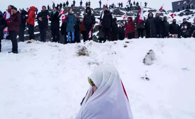 An Inuit girl draped in a national flag attends a protest against Trump's policy towards Greenland in front of the US consulate in Nuuk, Greenland, Saturday, Jan. 17, 2026. (AP Photo/Evgeniy Maloletka)