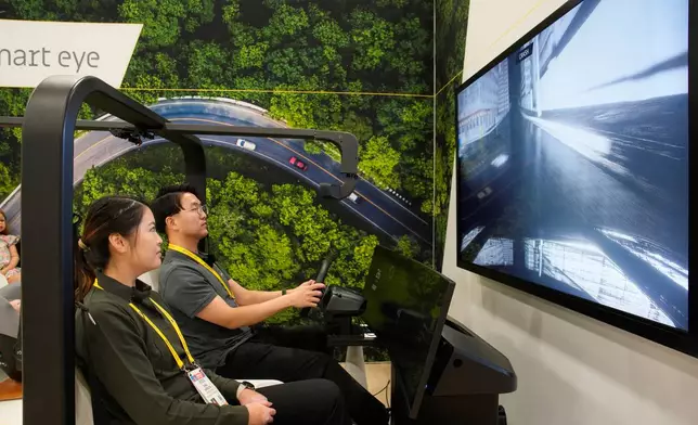 People take part in a simulator for Smart Eye interior sensing AI technology at the Smart Eye booth during the CES tech show Tuesday, Jan. 6, 2026, in Las Vegas. (AP Photo/John Locher)