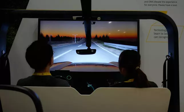 People take part in a simulator for Smart Eye interior sensing AI technology at the Smart Eye booth during the CES tech show Tuesday, Jan. 6, 2026, in Las Vegas. (AP Photo/John Locher)