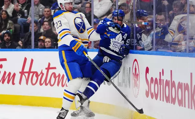 Buffalo Sabres' Mattias Samuelsson (23) and Toronto Maple Leafs' John Tavares (91) collied along the boards during the second period of an NHL hockey game in Toronto, Tuesday, Jan. 27, 2026. (Frank Gunn/The Canadian Press via AP)