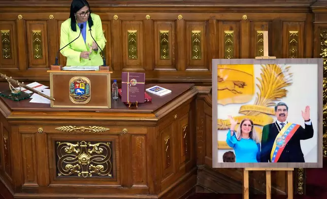Venezuela's acting President Delcy Rodriguez addresses lawmakers next to a picture of former President Nicolas Maduro and his wife Cilia Flores, at the National Assembly in Caracas, Venezuela, Thursday, Jan. 15, 2026. (AP Photo/Ariana Cubillos)