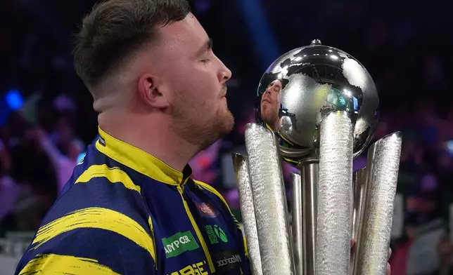 England's Luke Littler lifts the trophy after winning the World Darts Championships final match against Gian van Veen of the Netherlands at Alexandra Palace in London, Saturday, Jan. 3, 2026.(AP Photo/Dave Shopland)