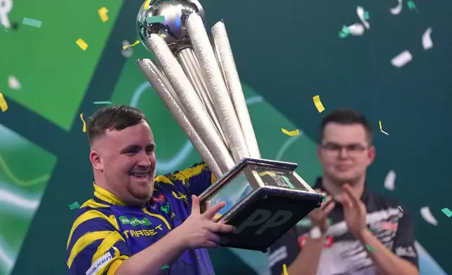 England's Luke Littler lifts the trophy after winning the World Darts Championships final match against Gian van Veen of the Netherlands at Alexandra Palace in London, Saturday, Jan. 3, 2026.(AP Photo/Dave Shopland)