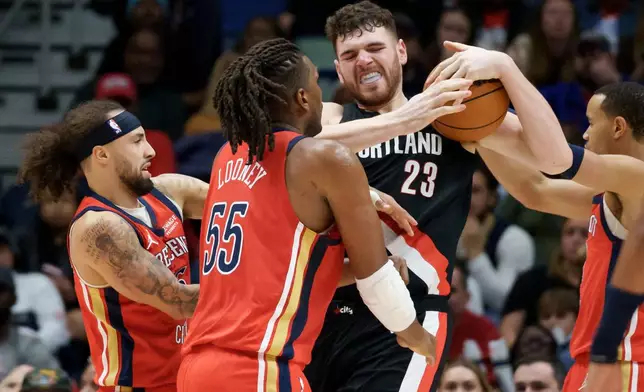 Portland Trail Blazers center Donovan Clingan (23) battles for the ball with New Orleans Pelicans guard Jose Alvarado, left, and forward Kevon Looney (55) during the first half of an NBA basketball game in New Orleans, Friday, Jan. 2, 2026. (AP Photo/Matthew Hinton)