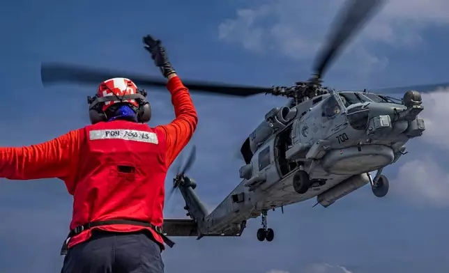 This photo provided by the U.S. Navy shows Aviation Ordnanceman 3rd Class Dianna Hernandez directs an MH-60R Sea Hawk helicopter on the flight deck of the Nimitz-class aircraft carrier USS Abraham Lincoln in the Indian Ocean on Jan. 21, 2026. (Mass Communication Specialist Seaman Daniel Kimmelman/U.S. Navy via AP)