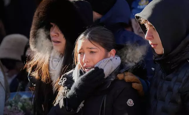 Mourners cry as they attend a memorial march in Crans-Montana, Swiss Alps, Switzerland, Sunday, Jan. 4, 2026, after a devastating fire in Le Constellation bar left dead and injured during the New Year's celebrations. (AP Photo/Baz Ratner)