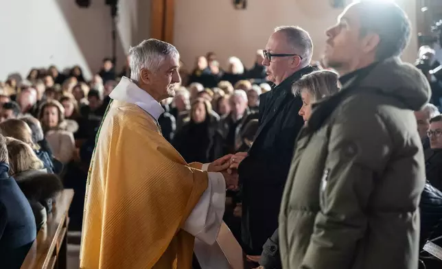 Bishop Monseigneur Jean-Marie Lovey, left, greets Nicolas Feraud, President of Crans-Montana ahead of a Sunday mass at the Chapelle St-Christophe, dedicated to the victims of the fire at the 'Le Constellation' bar and lounge, in Crans-Montana, Switzerland, on Sunday, Jan. 4, 2026. (Jean-Christophe Bott/Keystone via AP)