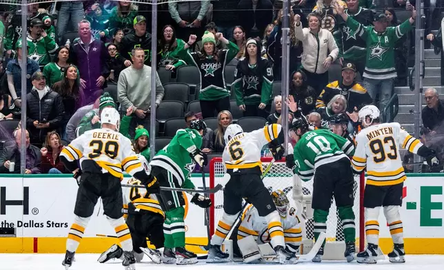 Dallas Stars left wing Jamie Benn, left, and center Oskar Bäck (10) look closely at a shot by Stars center Justin Hryckowian, not shown, as it slides past Boston Bruins goaltender Jeremy Swayman (1) and Bruins' Morgan Geekie (39), center Mark Kastelic (47), defenseman Mason Lohrei (6) and Fraser Minten (93) look on during the second period of an NHL hockey game, Tuesday, Jan. 20, 2026, in Dallas. (AP Photo/Jeffrey McWhorter)