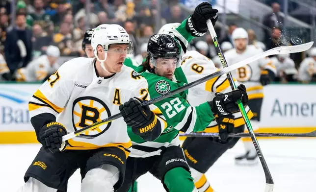 Boston Bruins defenseman Hampus Lindholm (27) and Dallas Stars center Mavrik Bourque (22) compete for the puck during the first period of an NHL hockey game, Tuesday, Jan. 20, 2026, in Dallas. (AP Photo/Jeffrey McWhorter)