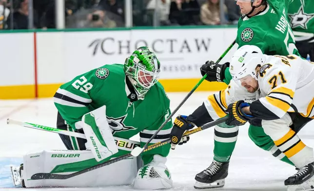 Dallas Stars goaltender Jake Oettinger (29) covers up the puck as Boston Bruins left wing Viktor Arvidsson (71) tangles with Stars defenseman Thomas Harley during the second period of an NHL hockey game, Tuesday, Jan. 20, 2026, in Dallas. (AP Photo/Jeffrey McWhorter)