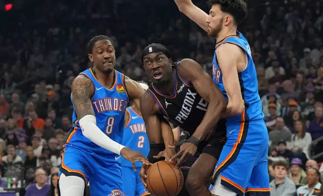 Phoenix Suns center Mark Williams drives between Oklahoma City Thunder guard Jalen Williams (8) and center Chet Holmgren during the first half of an NBA basketball game, Sunday, Jan. 4, 2026, in Phoenix. (AP Photo/Rick Scuteri)
