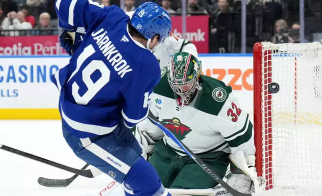 Minnesota Wild goaltender Filip Gustavsson (32) makes a save on Toronto Maple Leafs forward Calle Jarnkrok (19) during the second period of an NHL hockey game in Toronto, Monday, Jan. 19, 2026. (Nathan Denette/The Canadian Press via AP)