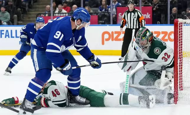 Minnesota Wild goaltender Filip Gustavsson (32) makes a save on Toronto Maple Leafs forward John Tavares (91) during the second period of an NHL hockey game in Toronto, Monday, Jan. 19, 2026. (Nathan Denette/The Canadian Press via AP)