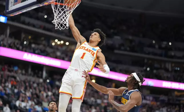Atlanta Hawks forward Jalen Johnson, left, goes up for a basket as Denver Nuggets center DaRon Holmes defends in the first half of an NBA basketball game Friday, Jan. 9, 2026, in Denver. (AP Photo/David Zalubowski)