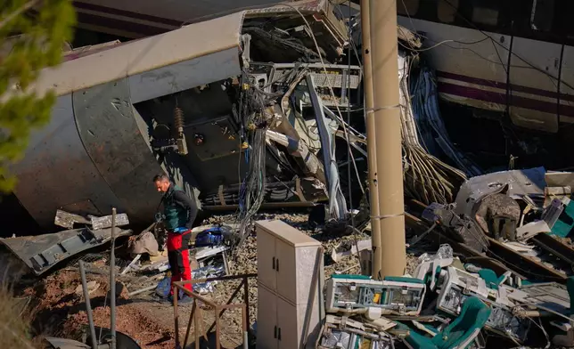 Guardia Civil officers collect evidence next to the wreckage of train cars involved in a collision in Adamuz, southern Spain, Tuesday, Jan. 20, 2026. (AP Photo/Manu Fernandez)