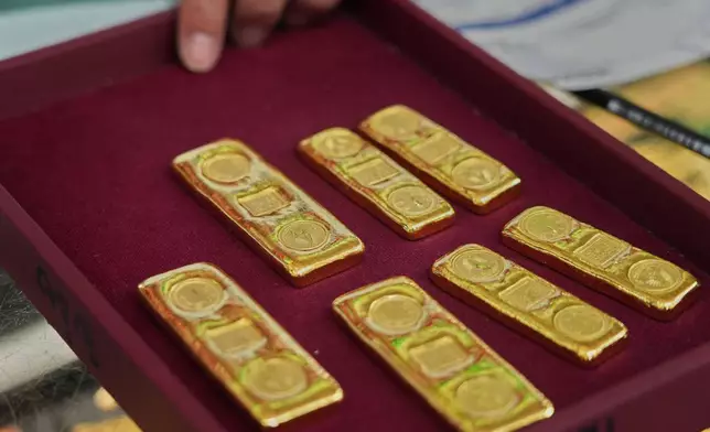 A customer puts gold bars on a basket at a gold shop in Bangkok, Thailand, Thursday, Jan. 29, 2026. (AP Photo/Sakchai Lalit)