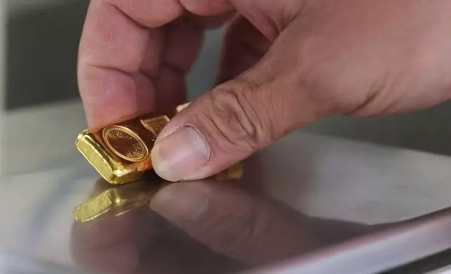 A gold jeweler weighs a gold bar for sale in Bangkok, Thailand, Thursday, Jan. 29, 2026. (AP Photo/Sakchai Lalit)