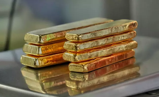A gold jeweler weighs gold bars for sale in Bangkok, Thailand, Thursday, Jan. 29, 2026. (AP Photo/Sakchai Lalit)